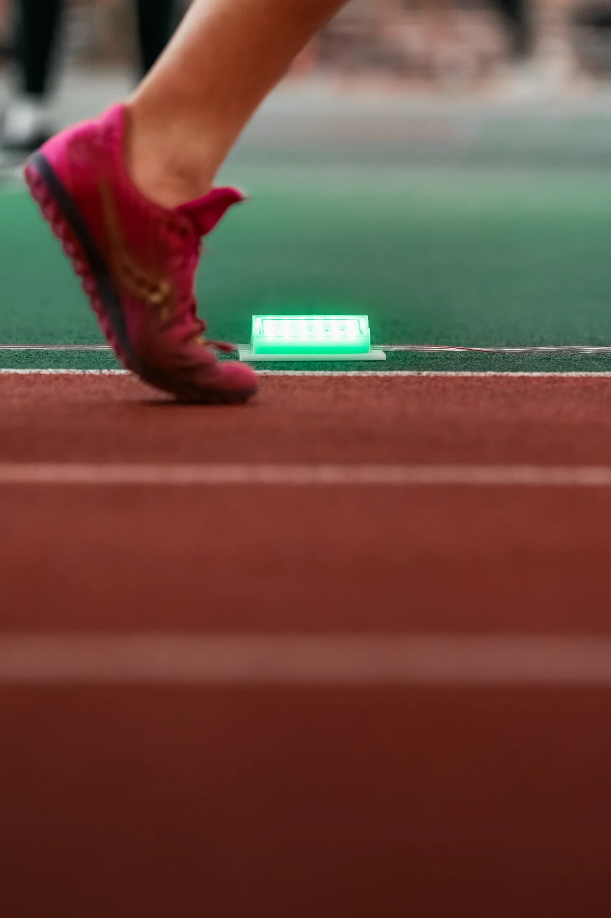Runner passing a glowing Stridelane pacing light on the track