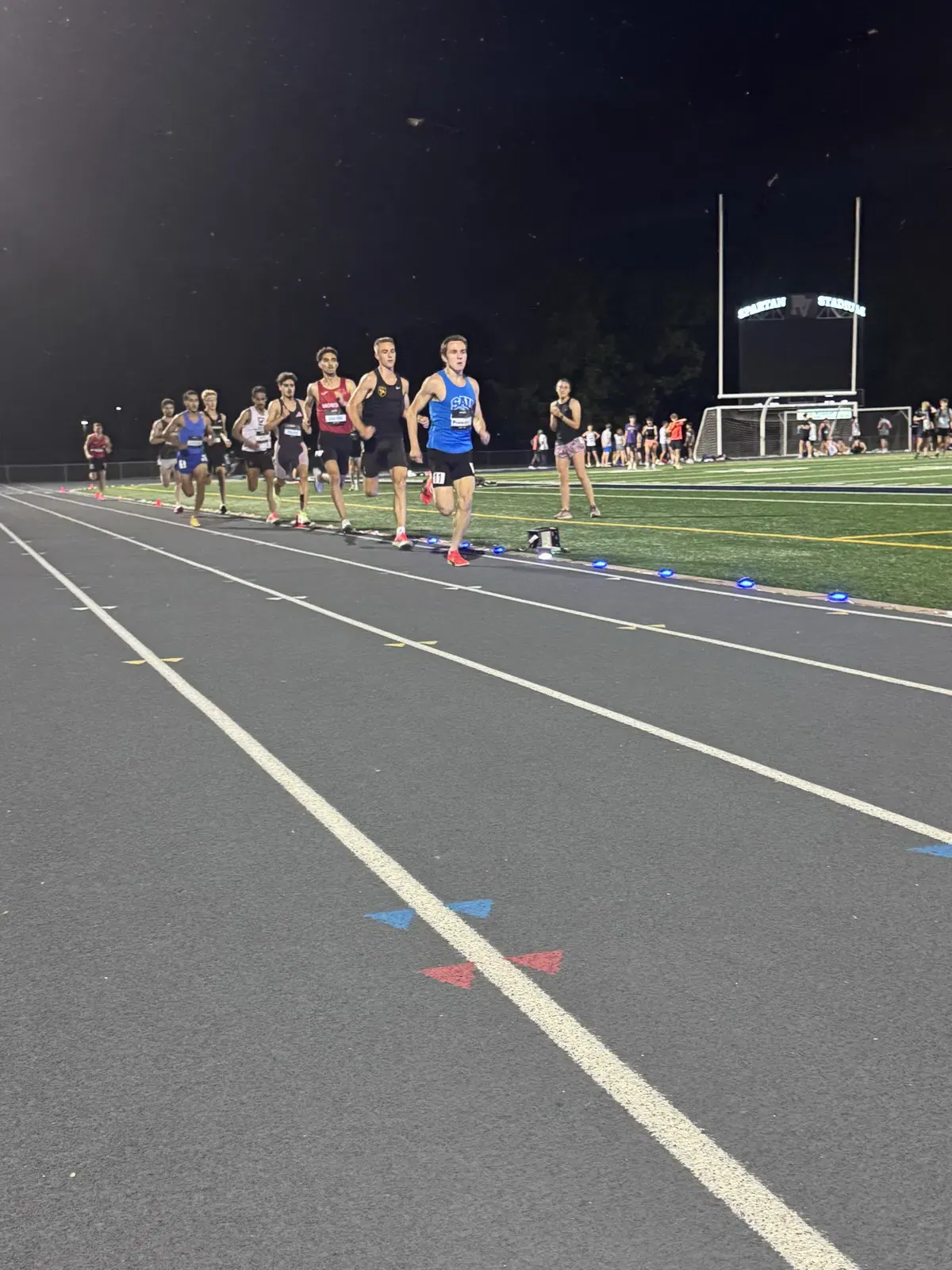 Athletes racing on an outdoor track with Stridelane lights along the rail
