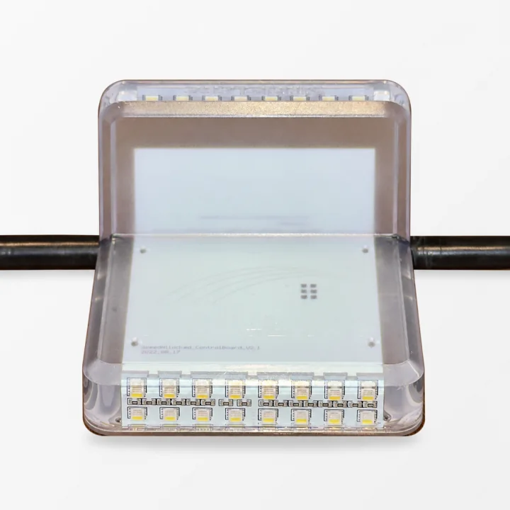 Front view of a clear Stridelane pacing-light module with two rows of LEDs and its continuous cable