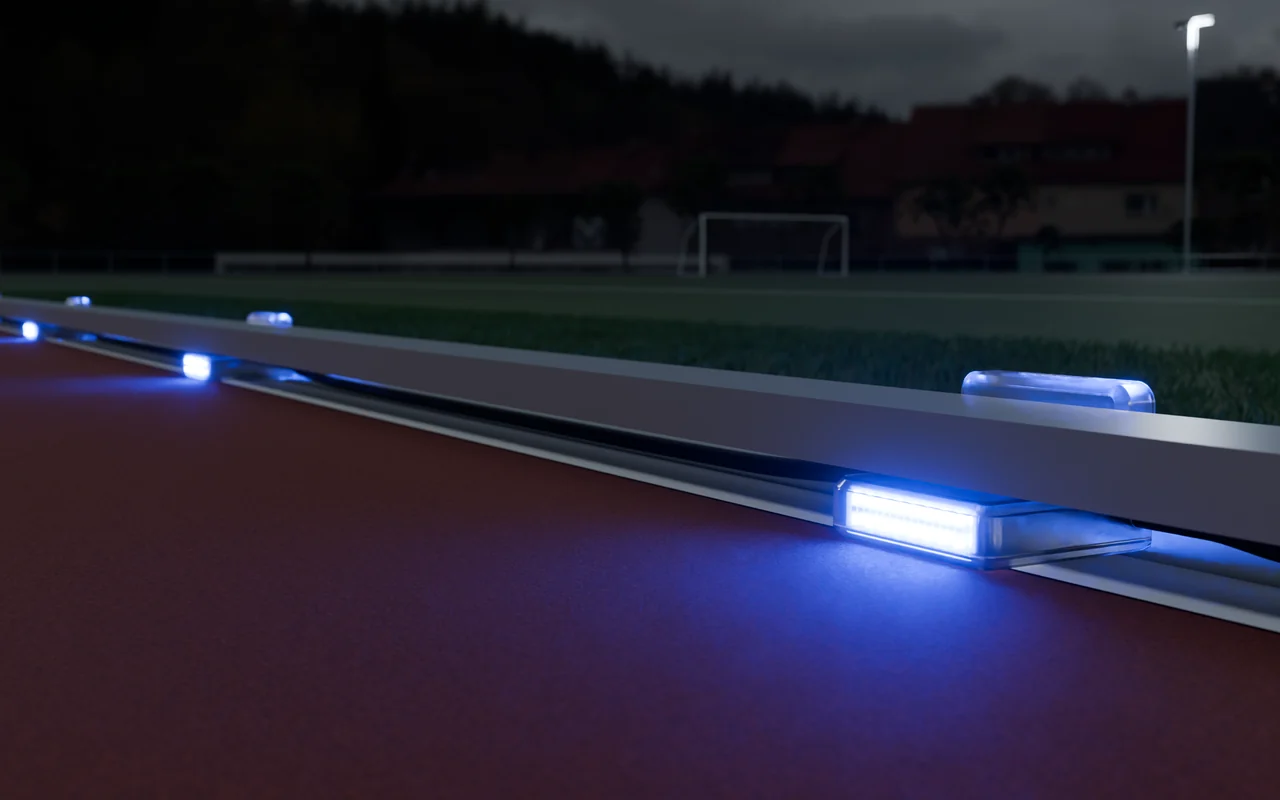 Blue Stridelane pacing lights connected along the inside curb of a generic outdoor track at dusk